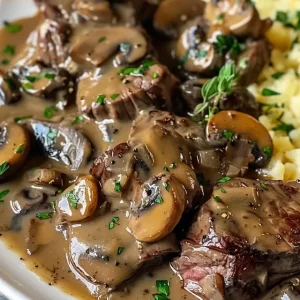 Close-up of tender cubed steak in a rich mushroom gravy, served with mashed potatoes.