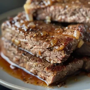 Close-up of a cube steak smothered in a rich brown gravy with sauteed mushrooms.