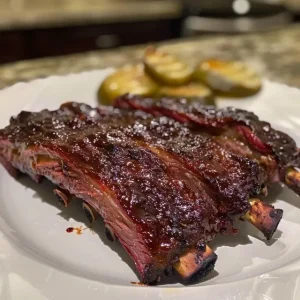 Three pieces of breaded and fried boneless venison ribs on a dark surface.