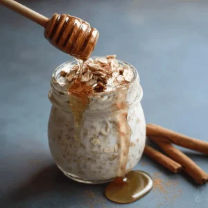 Overhead close-up of a bowl of cinnamon roll overnight oats, topped with a swirl of cream and cinnamon.