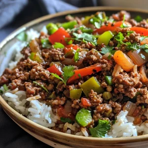 A side view of rice topped with seasoned ground beef and sliced peppers in a bowl.