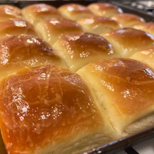 Juicy and warm cast iron dinner rolls glistening with melted butter.