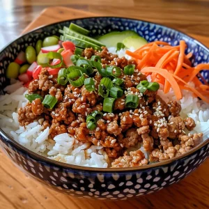 Appetizing ground turkey rice bowl featuring sliced cucumbers and shredded carrots.