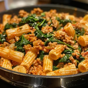 Juicy ground turkey mixed with spinach and pasta in a close-up shot, highlighting the dish's textures.