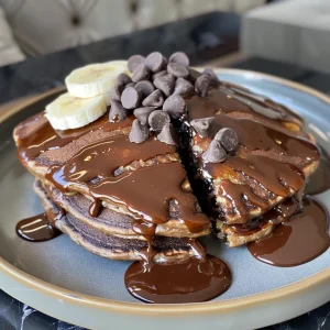 Side view of delicious chocolate pancakes stacked high on a plate.