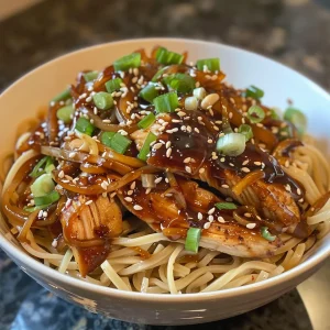 Close-up of juicy teriyaki chicken noodle bowl, featuring glazed chicken and colorful vegetables.