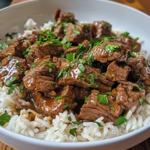 A close-up view of tender beef tips served over white rice, garnished with fresh parsley.