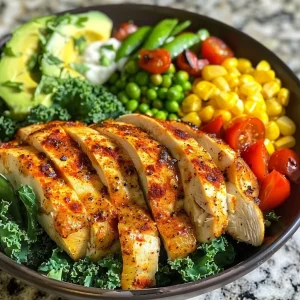 A close-up side view of a Chicken Ranch Kale & Quinoa Bowl with vibrant vegetables and sliced chicken.