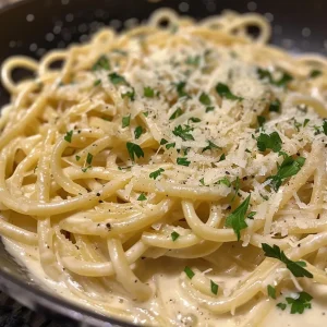 Close-up view of creamy garlic pasta garnished with herbs.