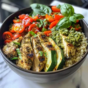 Close-up view of a vibrant Pesto Chicken Quinoa Bowl featuring chicken, zucchini, and cherry tomatoes.