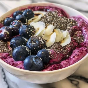 ['Close-up of creamy blueberry coconut chia pudding topped with fresh blueberries.', 'Side view of a colorful bowl of blueberry coconut chia pudding, garnished with coconut chips.', 'Juicy blueberry chia pudding in a transparent bowl, showcasing its layered texture.', 'Rich-looking chia pudding with blueberries, coconut cream, and a drizzle of honey.']