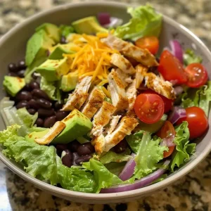 ['Close-up of a colorful Chicken Taco Salad featuring fresh ingredients.', 'Side view of a Chicken Taco Salad with layers of lettuce, chicken, and toppings.', 'Juicy Chicken Taco Salad showcasing vibrant vegetables and creamy avocado slices.', 'Detailed shot of a Chicken Taco Salad with black beans, cherry tomatoes, and cheese.']