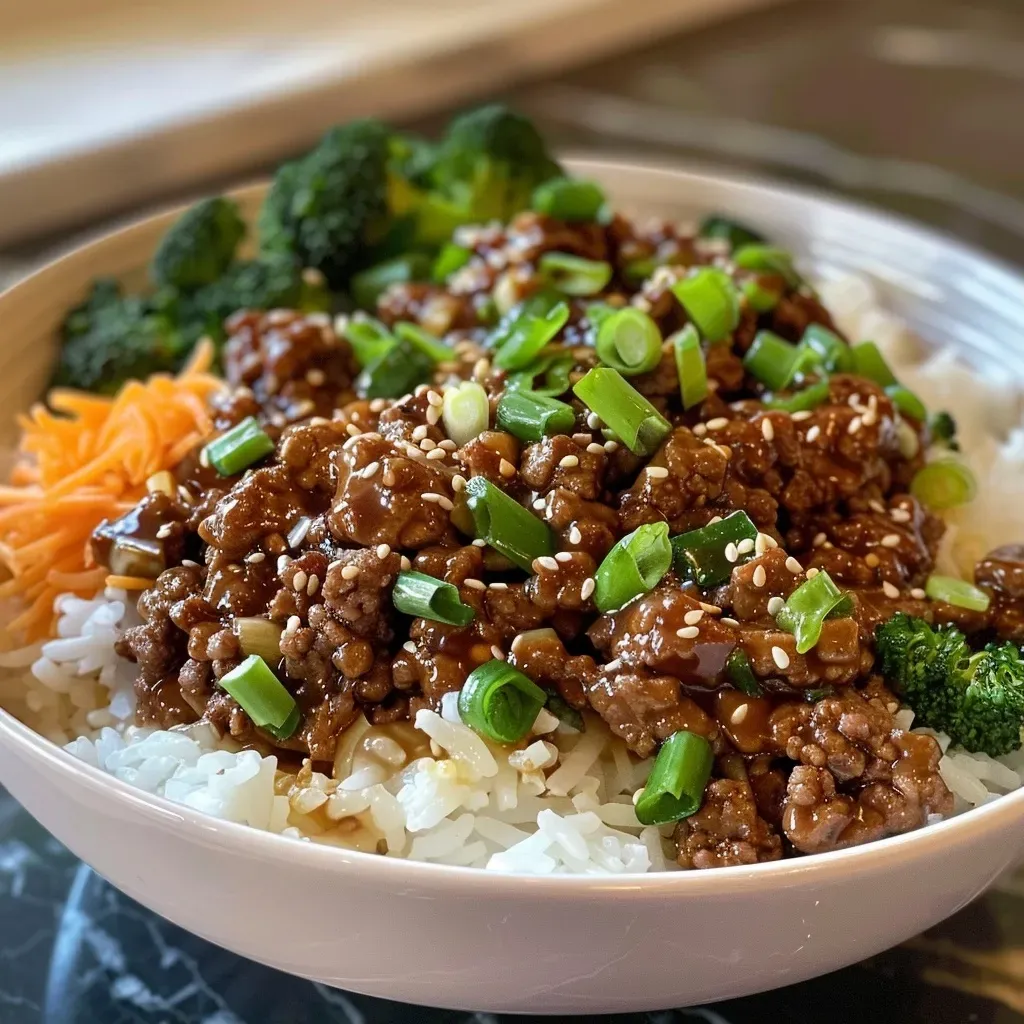 ['Close-up view of a Ground Beef Hot Honey Bowl with colorful vegetables and rice.', 'Juicy ground beef garnished with scallions and sesame seeds in a bowl.', 'A delicious serving of spicy ground beef with hot honey and steamed broccoli.', 'Side view of a Ground Beef Hot Honey Bowl filled with fluffy rice and fresh cilantro.']