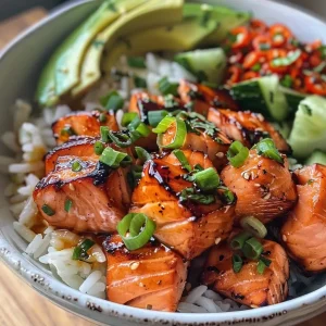 Close-up view of a bowl filled with Hot Honey Salmon, rice, diced cucumber, and avocado.