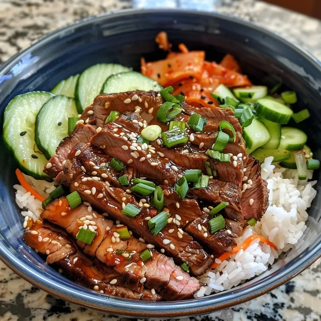 ['Close-up of a colorful Korean BBQ steak rice bowl with garnishes.', 'Side view of a hearty Korean BBQ steak rice bowl featuring fresh vegetables.', 'Juicy slices of flank steak atop a bed of rice, with vibrant veggies and sesame seeds.', 'Delicious Korean BBQ steak rice bowl loaded with cucumbers, carrots, and green onions.']