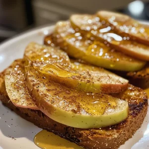 ['Close-up view of a slice of Apple Toast topped with Honey Butter and cinnamon, showcasing apple slices.', 'Side view of toasted whole wheat bread with peanut butter, apple slices, and a drizzle of honey.', 'Juicy Apple Toast with a glossy honey butter topping, featuring vibrant apple slices on toasted bread.', 'Toasted bread layered with peanut butter, fresh apple slices, and honey butter, viewed from the side.']
