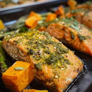 ['Juicy Baked Pesto Salmon fillet on a plate with colorful butternut rice and asparagus.', 'Close-up view of Baked Pesto Salmon served with butternut squash rice and green asparagus.', 'Baked Pesto Salmon dish showcasing vibrant butternut rice and lightly sautéed asparagus.', 'Deliciously presented Baked Pesto Salmon with a side of butternut rice and fresh asparagus.']