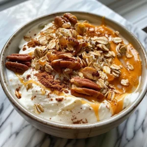 ['Close-up of a creamy pumpkin pie yogurt bowl garnished with chopped pecans and oats.', 'Side view of a luscious yogurt bowl featuring pumpkin puree and spices, topped with nuts.', 'Appetizing image of a pumpkin yogurt bowl with a rich texture and warm spices.', 'A colorful yogurt bowl filled with pumpkin ingredients, showcasing a delicious fall treat.']