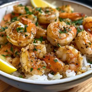 ['Close-up image of a bowl filled with Garlic Butter Shrimp over rice, garnished with parsley and lemon wedges.', 'Side view of a vibrant Garlic Butter Shrimp Rice Bowl featuring juicy shrimp, rice, and fresh herbs.', 'A delicious serving of Garlic Butter Shrimp Rice, showcasing succulent shrimp and a creamy sauce.', 'Detail of a Garlic Butter Shrimp Rice Bowl with shrimp, rice, and garnishes, emphasizing a flavorful meal.']