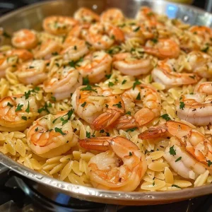 ['Close-up view of a bowl filled with One-Pot Garlic Butter Shrimp Orzo.', 'Juicy shrimp and orzo pasta dish, garnished with fresh parsley.', 'Side view of creamy One-Pot Garlic Butter Shrimp Orzo ready to serve.', 'A colorful dish of garlic butter shrimp mixed with orzo on a wooden table.']