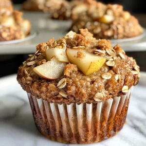 ['Close-up view of freshly baked Pear Cardamom Oatmeal Muffins with a golden crust.', 'Side view of moist Pear Cardamom Oatmeal Muffins, showing diced pear pieces on top.', 'Appetizing Pear Cardamom Oatmeal Muffins with a crumbly texture and cardamom seasoning.', 'Deliciously baked Pear Cardamom Oatmeal Muffins in a rustic muffin liner, ready to eat.']
