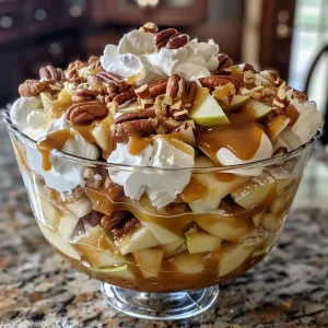 ['Close-up view of a layered Caramel Apple Trifle with visible apple pie filling and whipped topping.', 'Side angle showing a delicious Caramel Apple Trifle, featuring layers of caramel, apples, and pecans.', 'Detailed shot of a Caramel Apple Trifle with whipped cream and caramel drizzle, showcasing its ingredients.', 'Close-up of a trifle dessert highlighting layers of pound cake, pudding, and apple filling topped with caramel.']