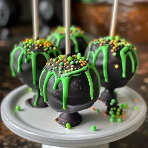['Close-up of Witches Cauldron Cake Pops with green and black colors.', "Deliciously crafted cake pops resembling witches' cauldrons, featuring green melts and sprinkles.", 'Side view of handmade cake pops shaped like cauldrons, showcasing vibrant colors.', 'Detailed view of spooky Witches Cauldron Cake Pops decorated with gel and candy melts.']